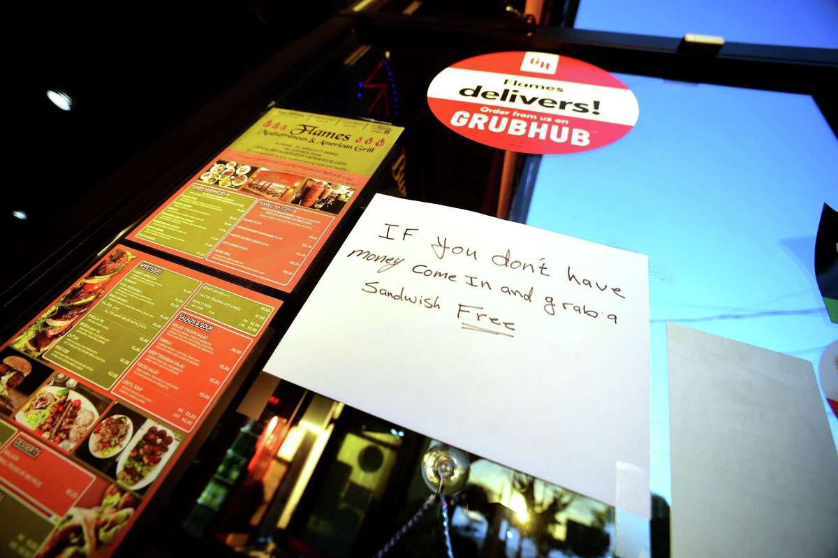 A sign on the front door of Flames Mediterranean & American Grill in Milford offers free sandwiches for those without money.