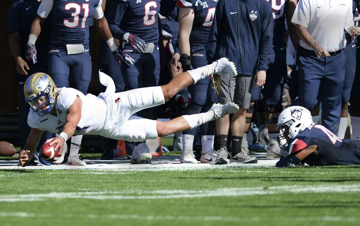 Tulsa quarterback Luke Skipper is taken down on the sidelines by UConn linebacker Darrian Beavers during the first half on Saturday.
