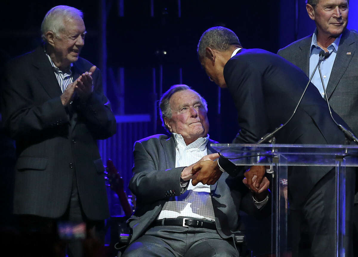 FILE - Former President Barack Obama goes up to shake George H.W. Bush's hand at the Deep From the Heart: The One America Appeal Concert in College Station, Texas. H.W. Bush's spokesman Jim McGrath apologized after actress Heather Lind accused the former president of sexual harassment during an AMC promotional tour.