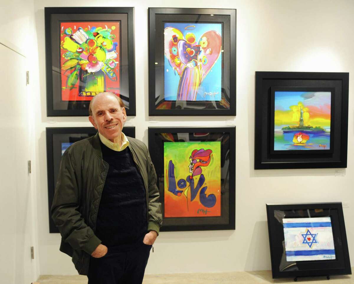 Renowned pop artist Peter Max poses by his work at the C. Parker Gallery in Greenwich, Conn. Sunday, Oct. 22, 2017. Max's work was on display Oct. 13 through Oct. 22 at the gallery and the artist made an appearance to chat with his fans on Saturday and Sunday.