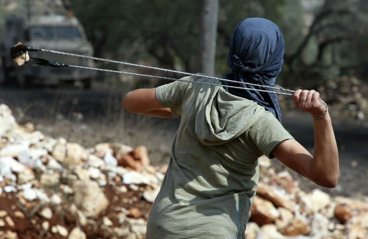 A Palestinian demonstrator uses his slingshot during clashes with Israeli forces following a weekly demonstration against the expropriation of Palestinian land by Israel in the village of Kfar Qaddum, near Nablus in the occupied West Bank on October 20. (Getty Images)