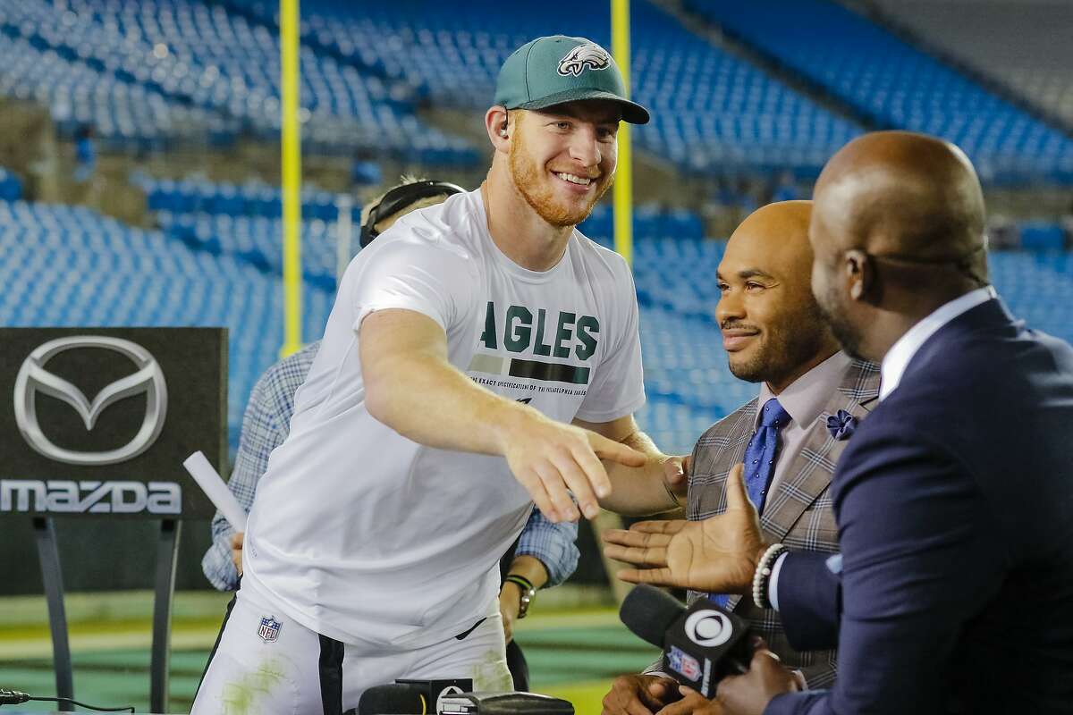 Philadelphia Eagles' Carson Wentz shakes the hand of Marshall Faulk as Steve Smith sits before the airing of the post game Thursday Night Football show following an NFL football game between the Philadelphia Eagles and Carolina Panthers in Charlotte, N.C., Thursday, Oct. 12, 2017. The Eagles won 28-23. (AP Photo/Bob Leverone)