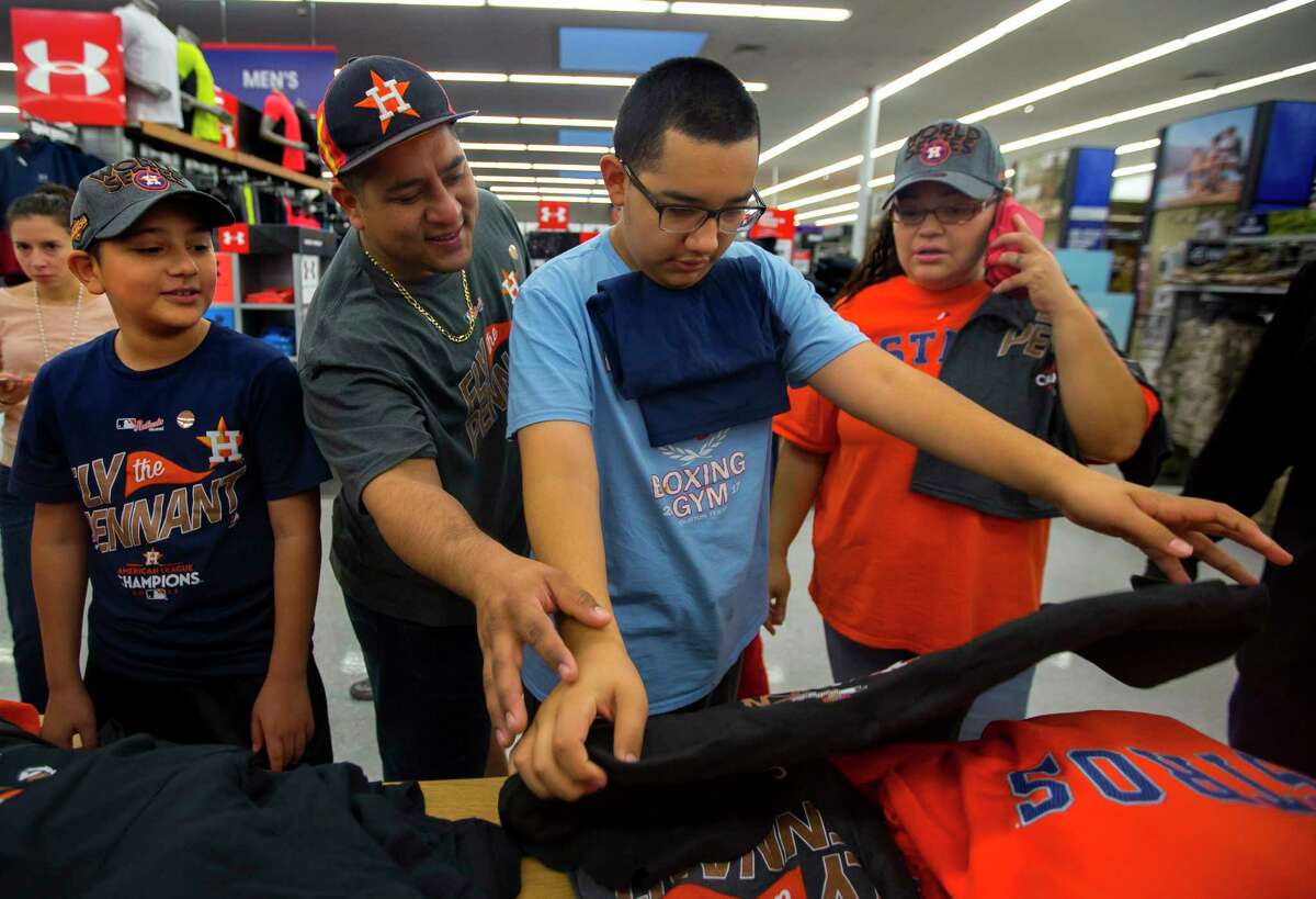 Armando Hercules, center, checks out Astros ALCS champion gear with his brother Antonio, left, and parents Carlos and Sandra at the Academy Sports + Outdoors location off of the Southwest Freeway on Sunday, Oct. 22, 2017, in Houston. The Hercules family has been awaiting a long time to see their beloved Astros in the World Series.
