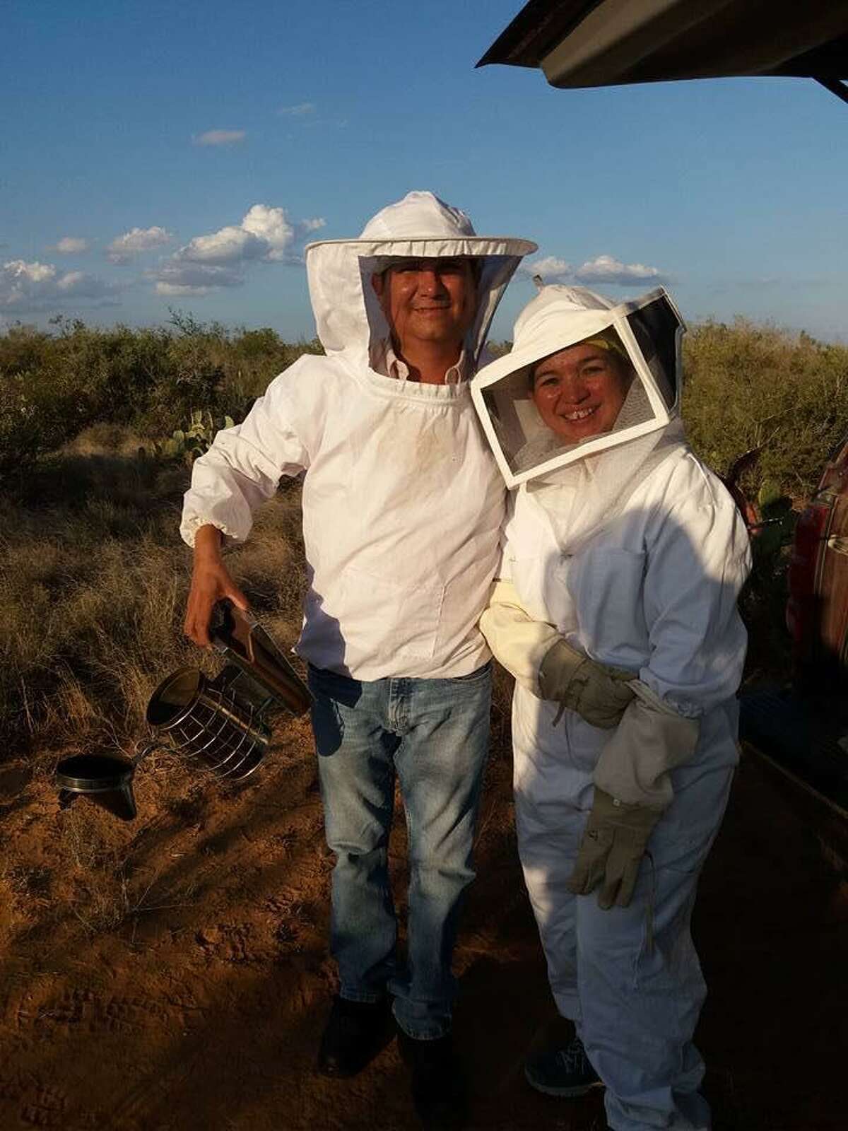 Alberto García y Norma Adriana Chapa de García portan sus trajes de apicultores mientras cosechan miel.