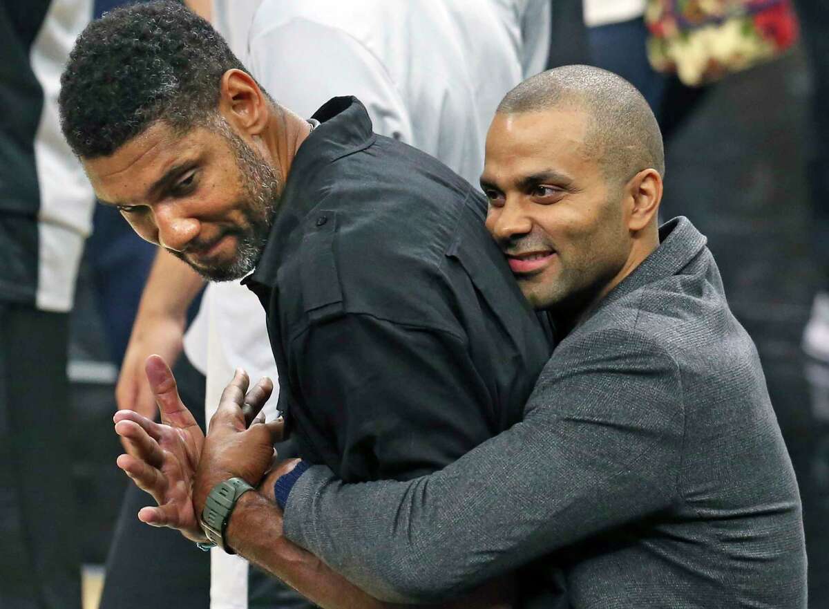 Tony Parker comes up from behind and hugs Tim Duncan who was on the court during pre game ceremonies as the Spurs play Minnesota in the season opener at the AT&T Center on October 18, 2017.