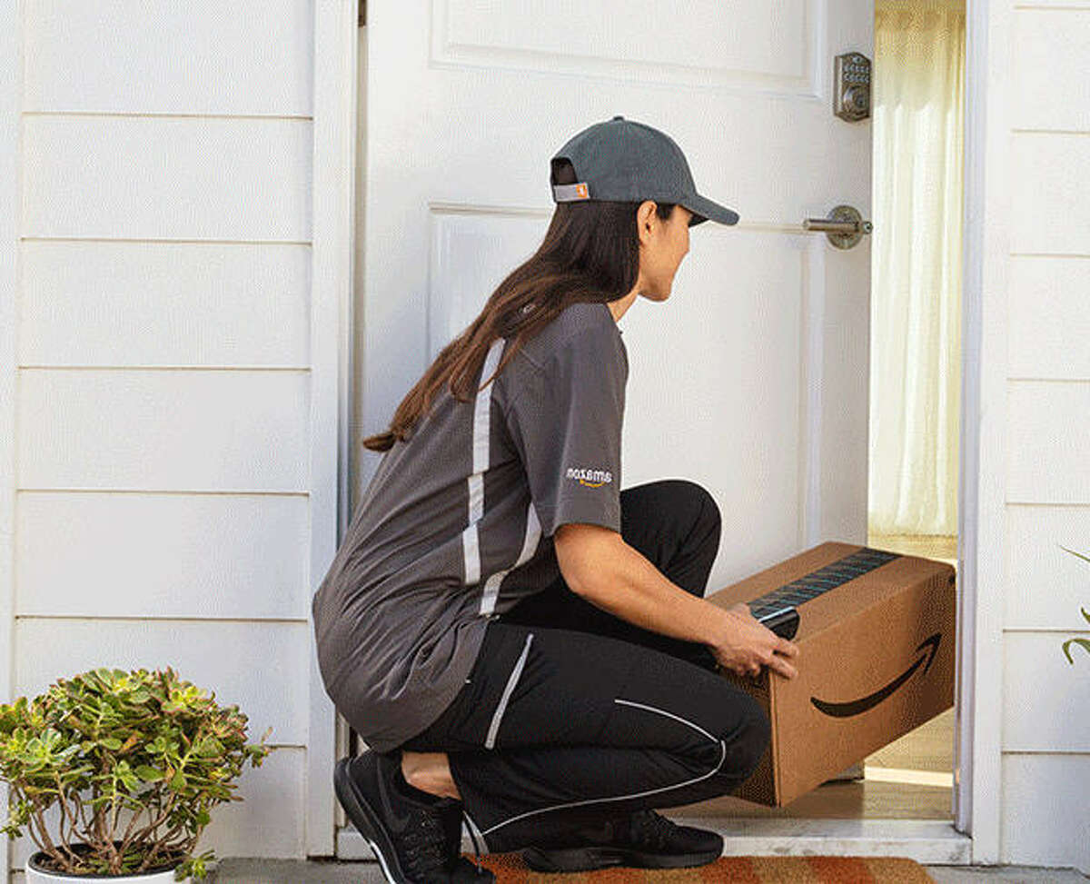 A delivery person places a package inside a customer's home using Amazon Key.