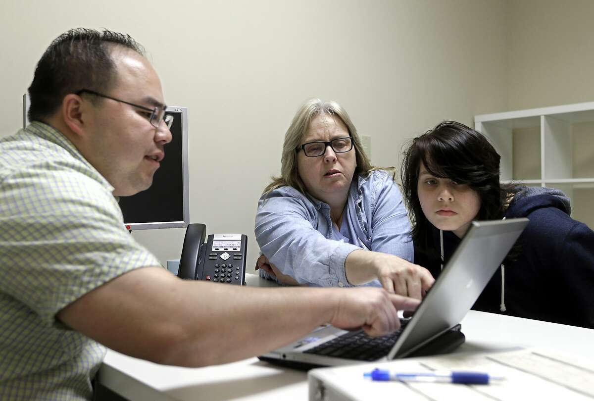 FILE - In this Feb. 12, 2015, file photo, Enrollment counselor Vue Yang, left, goes over some of the health insurance plans available to Laura San Nicolas, center, accompanied by her daughter, Geena, 17, while enrolling for health insurance at Sacramento Covered in Sacramento, Calif. Peter Lee, executive director of Covered California, announced, Tuesday, July 19, 2016, that the average monthly insurance premiums will increase by 13 percent next year for people who buy health care coverage through the state's insurance exchange. (AP Photo/Rich Pedroncelli,file)