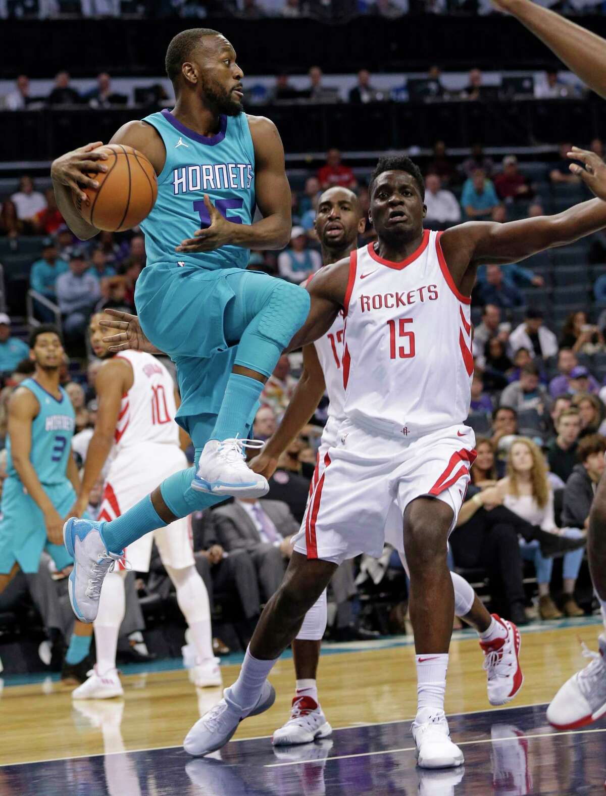 Charlotte Hornets' Kemba Walker, left, looks to pass the ball around Houston Rockets' Clint Capela, right, during the first half of an NBA basketball game in Charlotte, N.C., Friday, Oct. 27, 2017. (AP Photo/Chuck Burton)