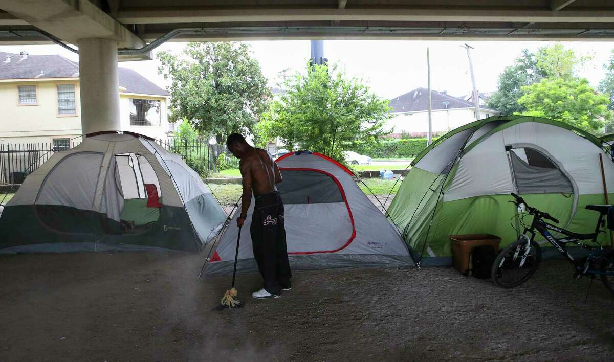 A man sweeps the area around his ﻿tent﻿ ﻿at an encampment under the U.S. 59 overpass near La Branch. Nearby residents say some transients are making life a living hell for those whose homes are immediately adjacent to the encampment.﻿