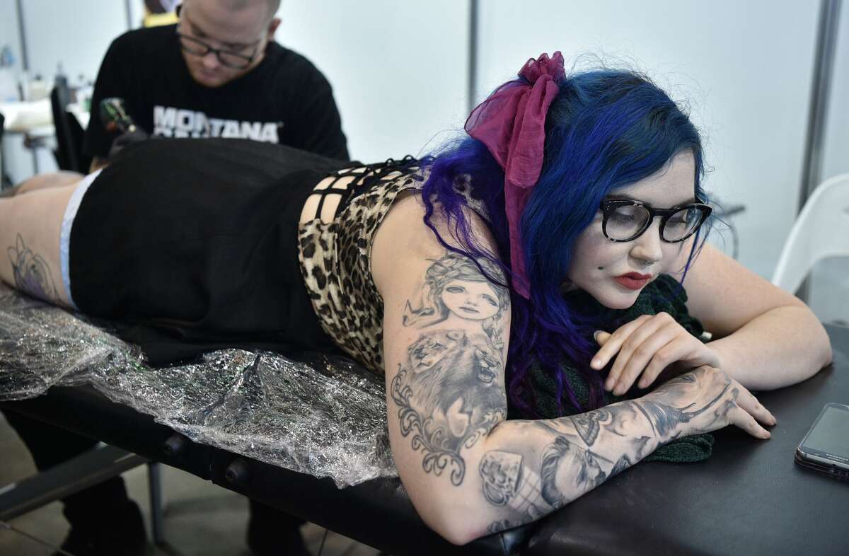 A tattoo artist (L) works on a visitor at the Rites of Passage tattoo festival event in Sydney on October 29, 2017. The annual Rites of Passage tattoo festival attracts more than 250 local and international tattoo artists to Australia. / AFP PHOTO / PETER PARKS (Photo credit should read PETER PARKS/AFP/Getty Images)