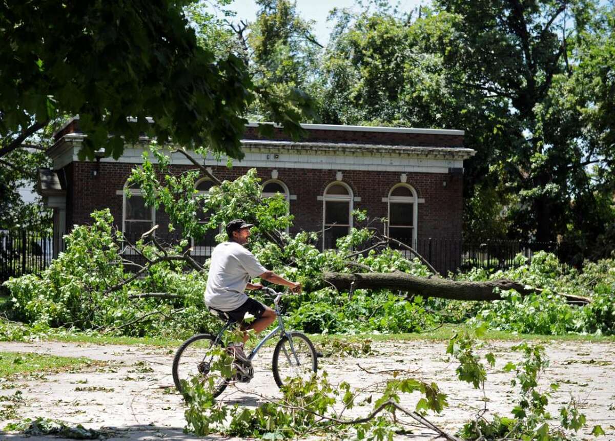 Tony Williamson, of Bridgeport, rides his bike past downed trees at Washington Park in Bridgeport Friday June 25, 2010. The damage was the result of a tornado with 100 mph winds that touched down in Bridgeport Thursday.