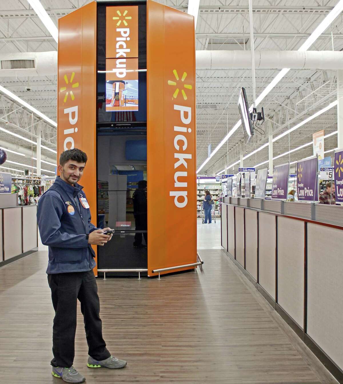 Sugar Land Wal-Mart associate Uzair Khan stands with the store's newly debuted Pickup Tower, which is designed to help busy customers save time.