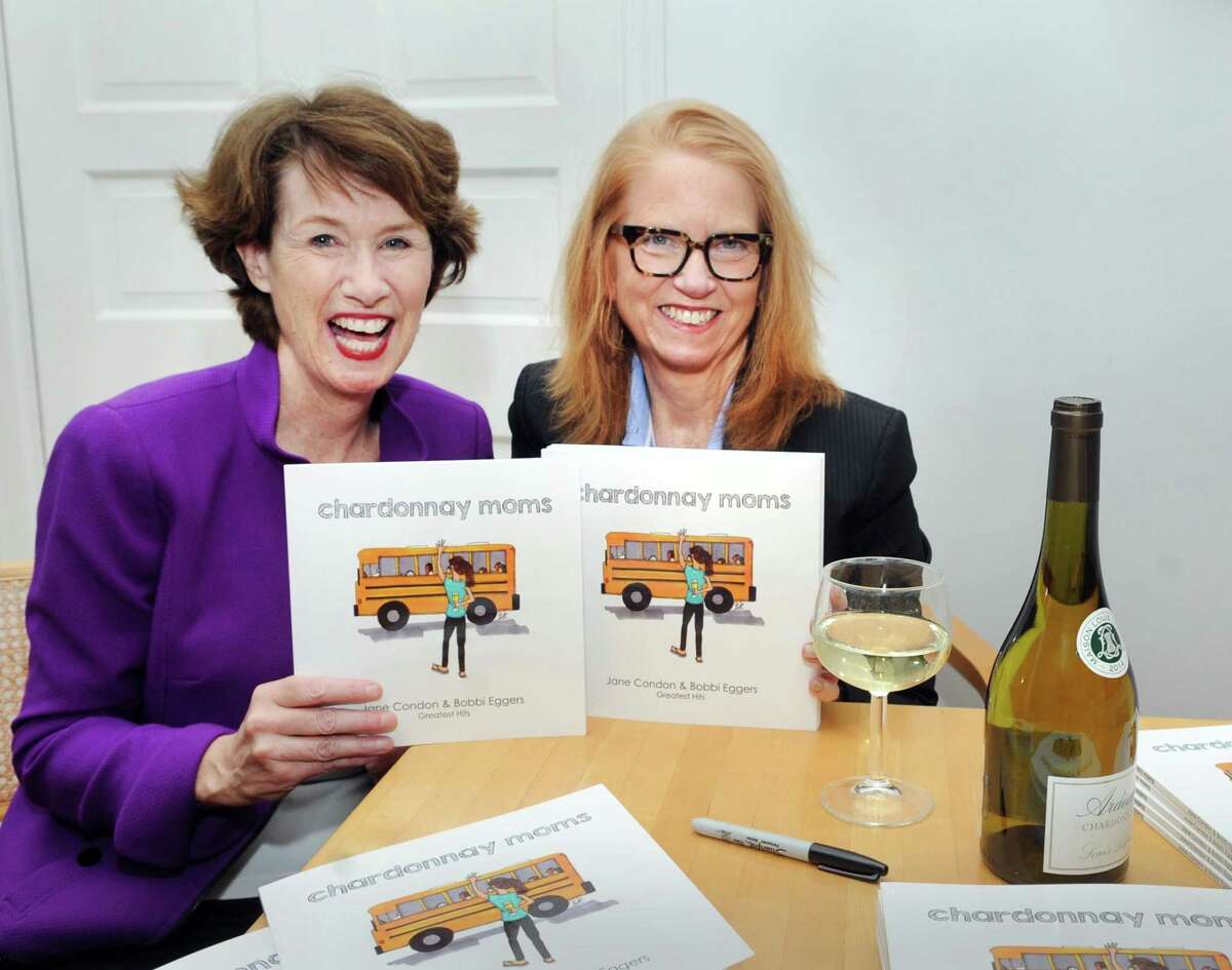 Jane Condon, left, and Bobbie Eggers, with their recently published book, “Chardonnay Moms,” featuring their greatest hits cartoons poking fun at the lighter side of Greenwich at Condon's home in Greenwich on Thursday.