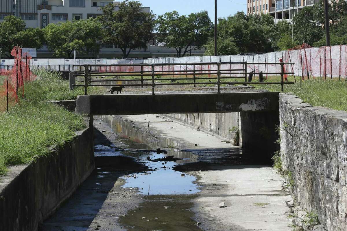 A cat crosses an old bridge across San Pedro Creek near West Travis Street in March 2017. The area is part of Phase 1 of the San Pedro Creek Improvement Project that will include two miles of channel, 4 miles of walkway, a community amphitheater and other amenities. The lower part of the retention wall, under the horizontal line, is historic and will be used in the project.