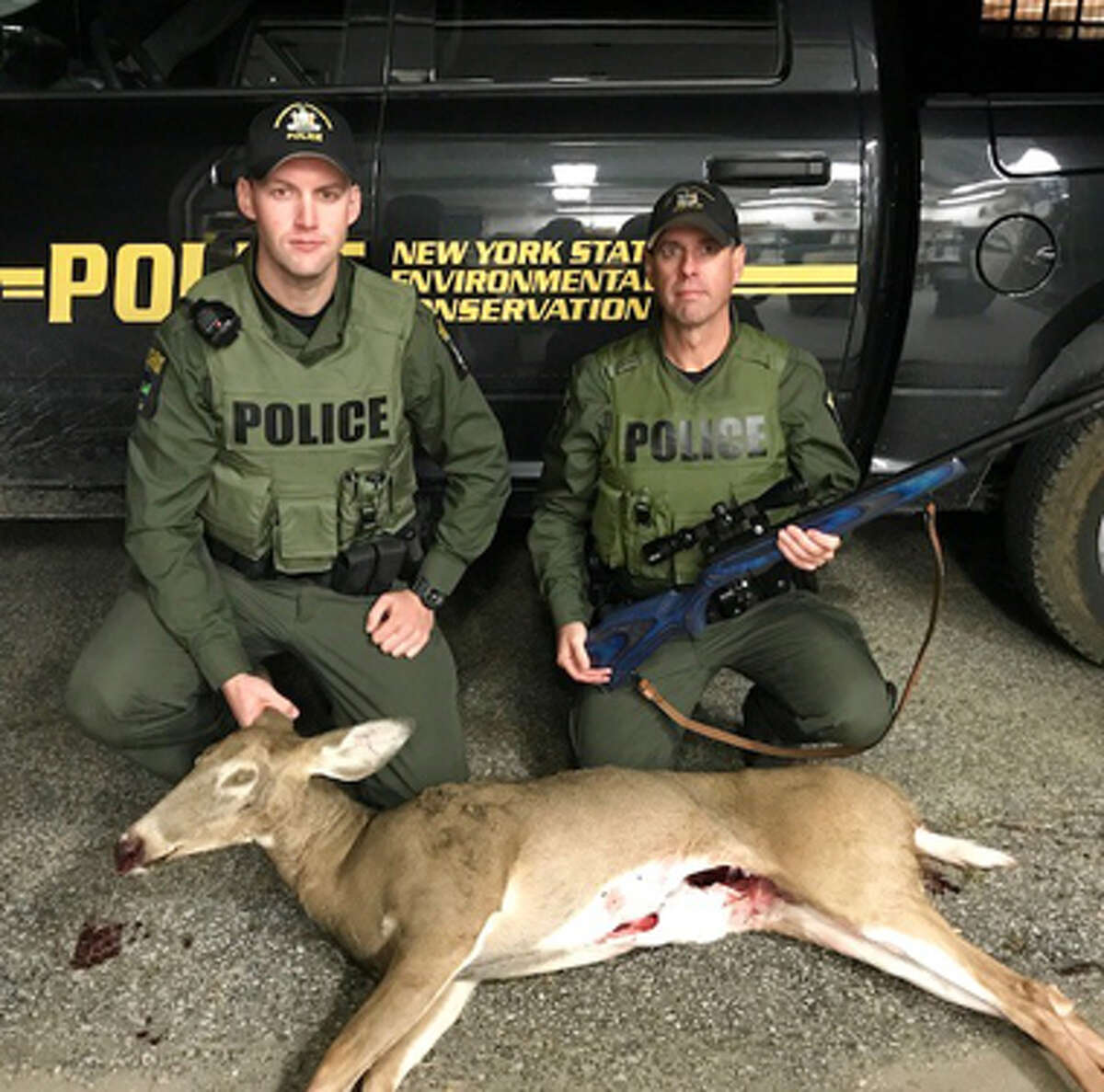 State Environmental Conservation Officers Steve Shaw and Ryan Kelley pose with an illegally taken deer and a seized rifle in Moreau, N.Y., on Oct. 17, 2017.