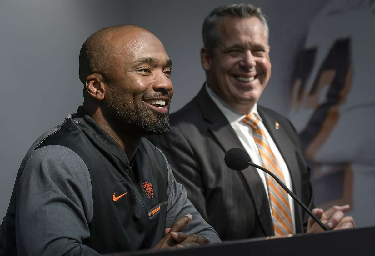 In this photo taken Oct. 9, 2017, Oregon State Vice President and Director of Athletics Scott Barns, right, and interim football coach Cory Hall attend a news conference in Corvallis, Ore., after head football coach Gary Andersen agreed to mutually part with the university. (Andy Cripe/The Corvallis Gazette-Times via AP)