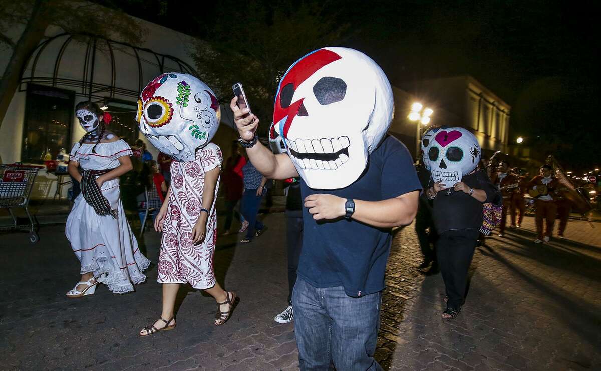 People wear oversized skeleton heads as they parade around the Laredo Center for the Arts Friday evening during the 'Caminarte Dia De Los Muertos' celebration.