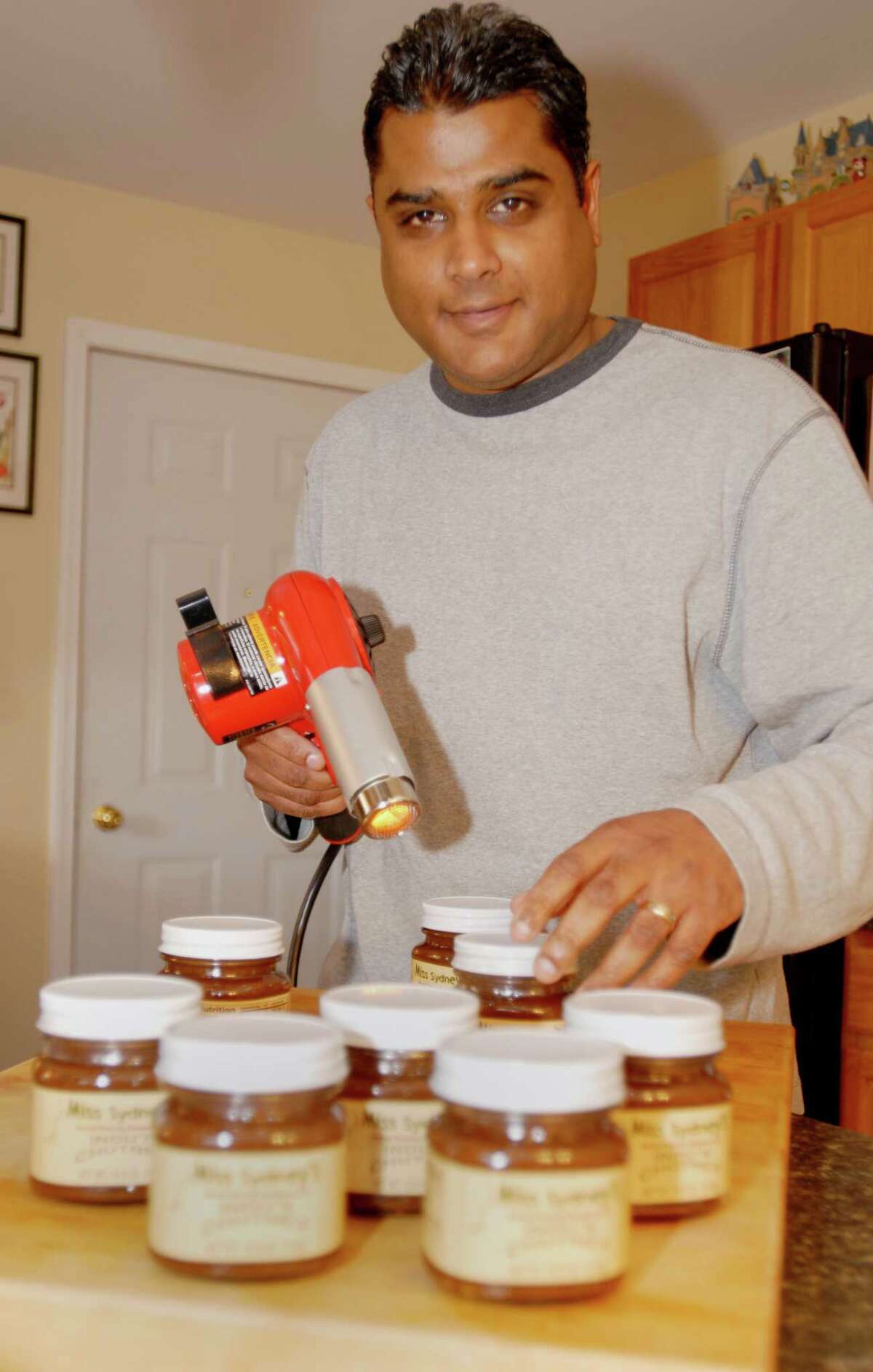 TIMES UNION PHOTO BY: LUANNE M. FERRIS--Monday, Feb. 11, 2008, Feura Bush, NY, Anand "A.J." Jayapal, cq., sealing the jars on some of his family's "Miss Sydney's Chutney, made from Indu's Secret Family Recipe", and their marinade, that they will present at the South Beach Wine and Food Show. The family, who is working together, with Anand's mom's Indian recipe and with help from his wife Shannon's parents, developed the products in their kitchen, and named the Chutney after their seven year old daughter Sydney. They currently produce their tasty condiments at Morrisville College, and are building a test kitchen at their home where they will assume production. Photos for a Feature centerpiece for a Food Centerpiece to package with Jenn Gish Story.