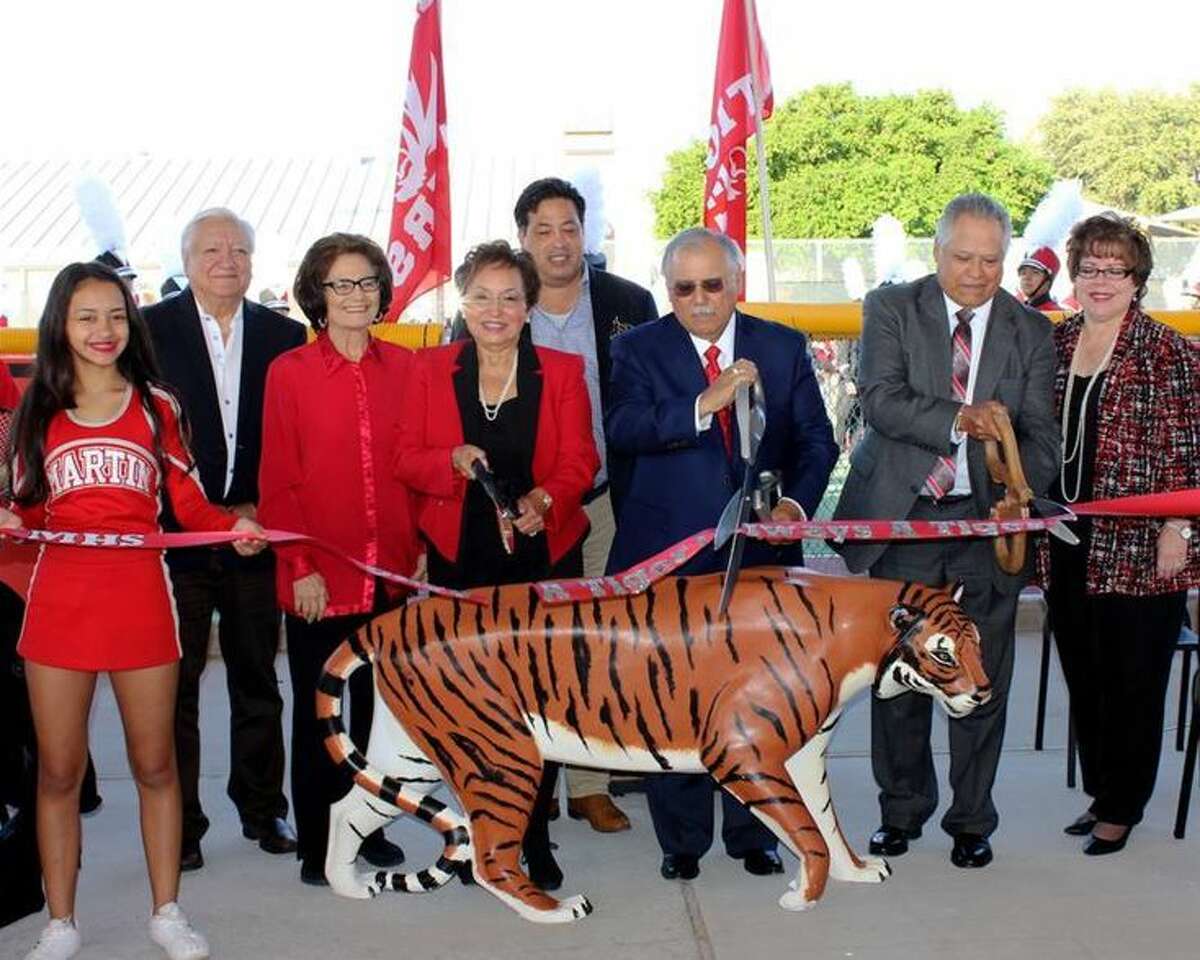 A Martin High School Cheerleader holds the ribbon as Dr. Alfredo Trevino, Tina Trevino and Fausto Dovalina, Jr. officially cut the ribbon for the new Martin High Trevino Tennis Court Complex and the Dovalina Championship Court. Pictured left to right are a Martin High School Cheerleader, LISD Board Secretary Hector Noyola, LISD board member Dr. Cecilia M. Moreno, Tina Trevino, LISD Board President Hector Garcia, Dr. Alfredo Trevino, Fausto Dovalina, Jr., and LISD Superintendent Dr. Sylvia Rios. 
