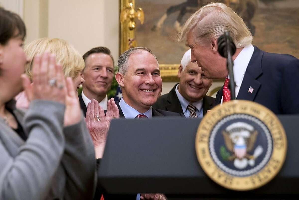 President Donald Trump shakes hands with Environmental Protection Agency (EPA) Administrator Scott Pruitt, center, before signing the Waters of the United States (WOTUS) executive order, Tuesday, Feb. 28, 2017, in the Roosevelt Room in the White House in Washington, which directs the Environmental Protection Agency to withdraw the Waters of the United States (WOTUS) rule, which expands the number of waterways that are federally protected under the Clean Water Act. (AP Photo/Andrew Harnik)