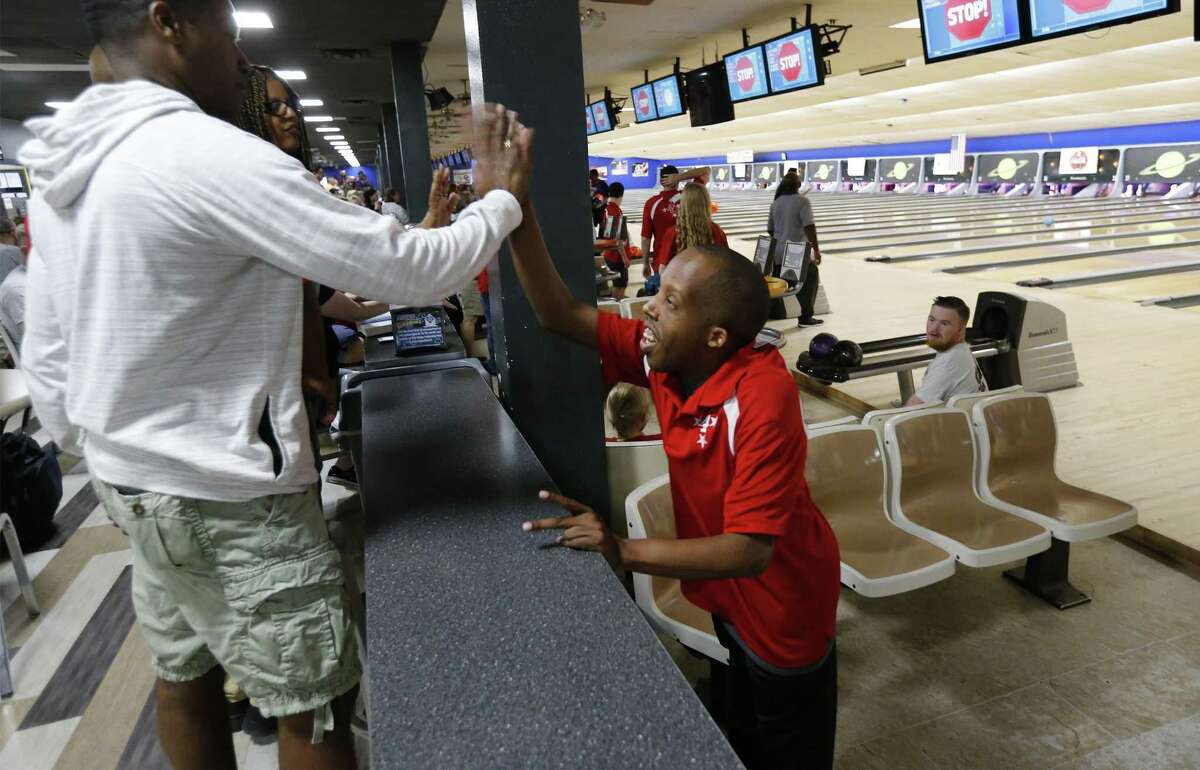 Special Olympian bowler Perry William McLaurin (right) gets a high-five from family friend Jason Childs (left) before the start of a bowling tournament at Astro Superbowl on Saturday, Nov. 4, 2017. Winners from the tournament qualify for the Special Olympics USA Games in 2018. McLaurin, 29, bowled a 186 in the first game and then a 163 in the final game to win a gold medal on Saturday. McLaurin is expected to take part in the 2018 national games to be held in Seattle. (Kin Man Hui/San Antonio Express-News)