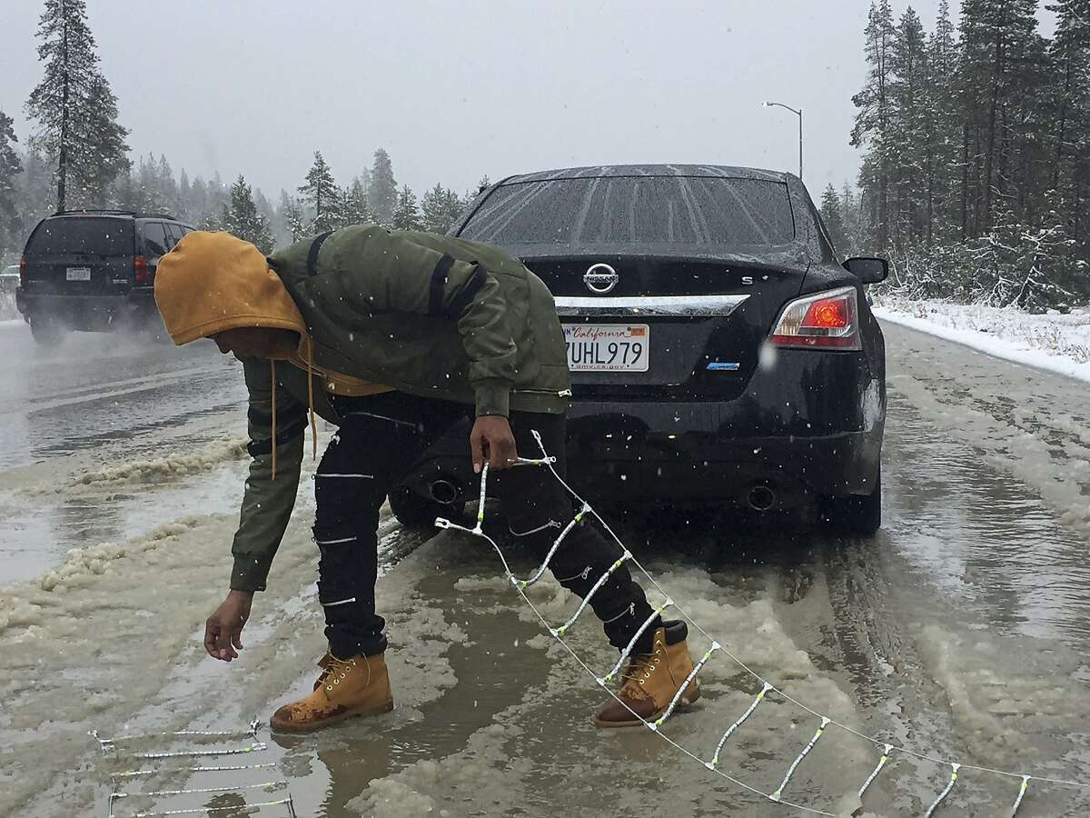 Ivory Williams of Sacramento removes chains from her friend's car during a snowstorm near Kingvale, Calif., on Saturday, Nov. 4, 2017. 