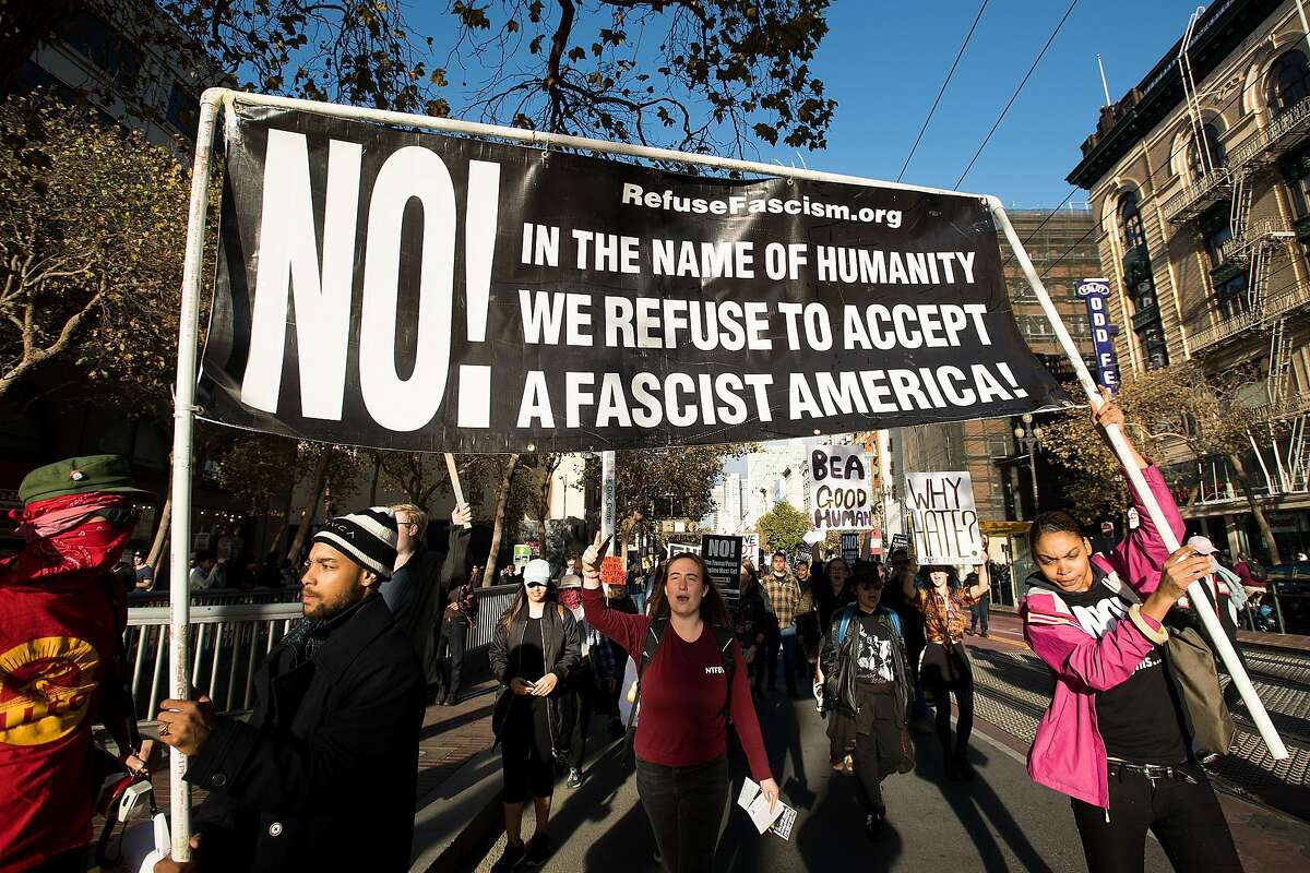 Alexis Moore, right, and Quayshion Smith, left, carry a banner while leading more than a hundred demonstrators against President Donald Trump down Market St. in San Francisco on Saturday, Nov. 4, 2017.