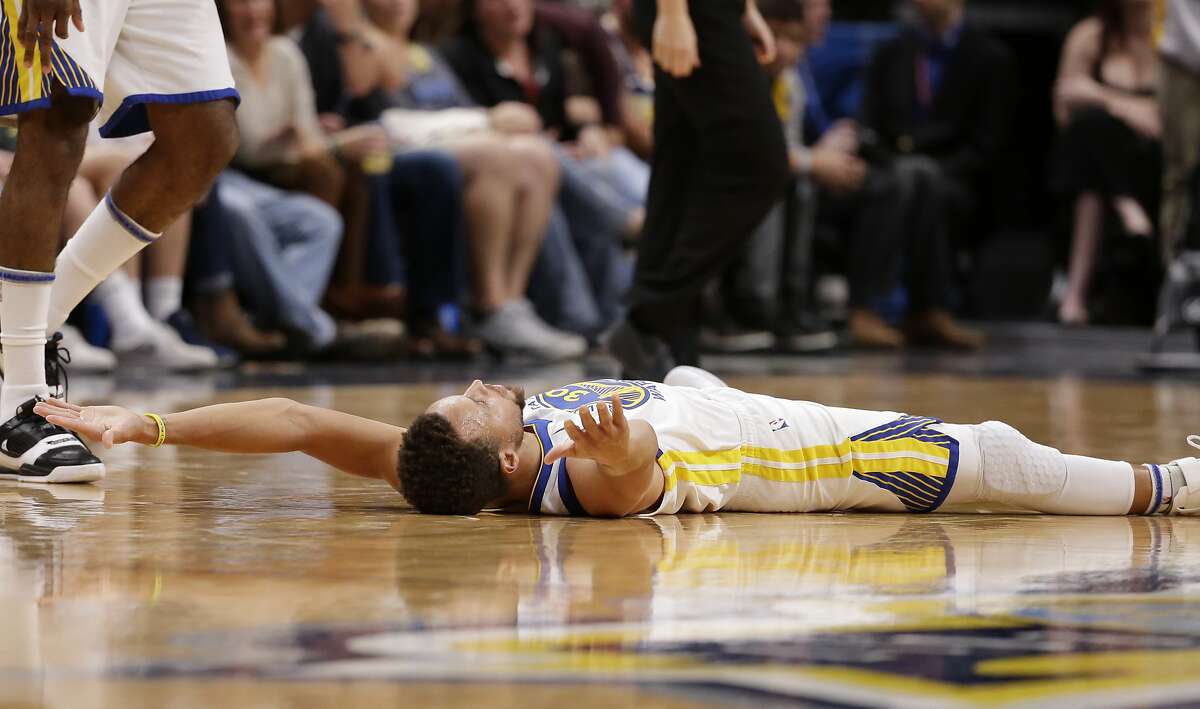 Golden State Warriors guard Stephen Curry lies on the court after hitting a three-point basket and drawing a foul during the third quarter of an NBA basketball game against the Denver Nuggets, Saturday, Nov. 4, 2017, in Denver. (Photo by Jack Dempsey)