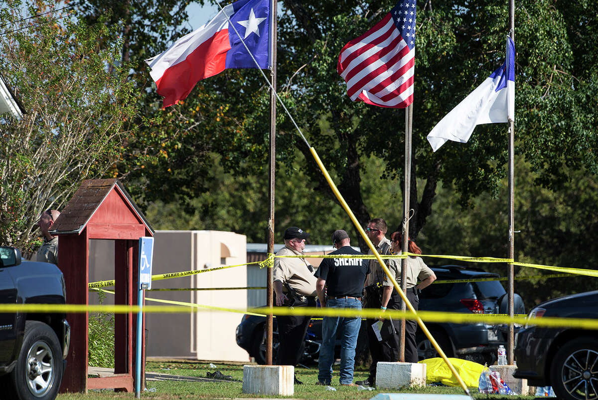Law enforcement officials stand next to a covered body at the scene of a fatal shooting at the First Baptist Church in Sutherland Springs, Texas, on Sunday, Nov. 5, 2017. (Nick Wagner/Austin American-Statesman via AP)