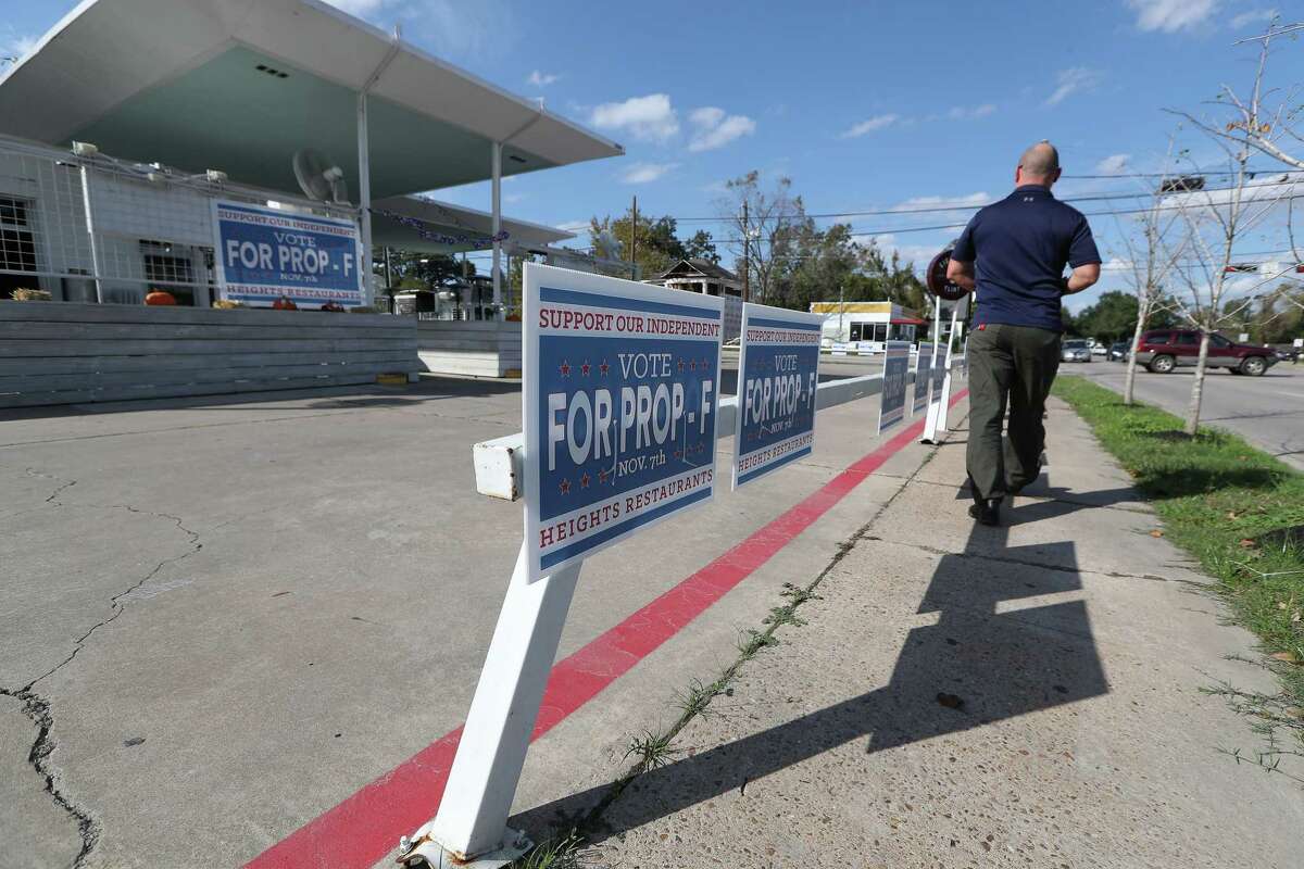 Bryan Davis walks in front of the Eight Row Flint, with signs of support for Prop F Monday, Nov. 6, 2017, in Houston.