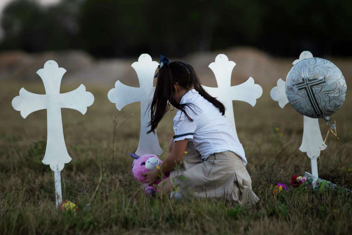 Heather Cooper, 8, leaves behind a stuffed animal by a cross representing one of the 26 lives killed during a shooting in the First Baptist Church of Sutherland Springs, Monday, Nov. 6, 2017, in Sutherland Springs.