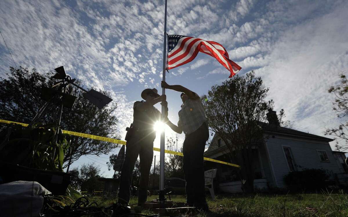 A law enforcement officer helps a man changes a flag to half-staff near the scene of a shooting at the First Baptist Church of Sutherland Springs to honor victims, Monday, Nov. 6, 2017, in Sutherland Springs, Texas. A man opened fire inside the church in the small South Texas community on Sunday, killing and wounding many. (AP Photo/Eric Gay)
