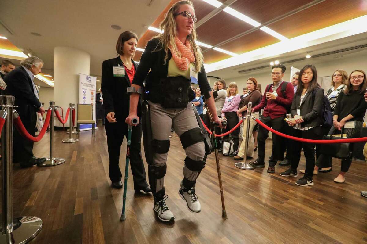 Erin Edenfield of TIRR Memorial Hermann ﻿demonstrates the Indego Exoskeletons Therapy kit with the help of Marcie Kern﻿ on Monday during the International Symposium on Wearable and Rehabilitation Robotics. ﻿