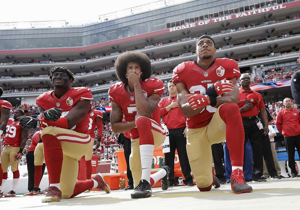 In this Oct. 2, 2016 file photo, from left, San Francisco 49ers outside linebacker Eli Harold, quarterback Colin Kaepernick and safety Eric Reid kneel in protest during the national anthem before an NFL football game against the Dallas Cowboys in Santa Clara, Calif.