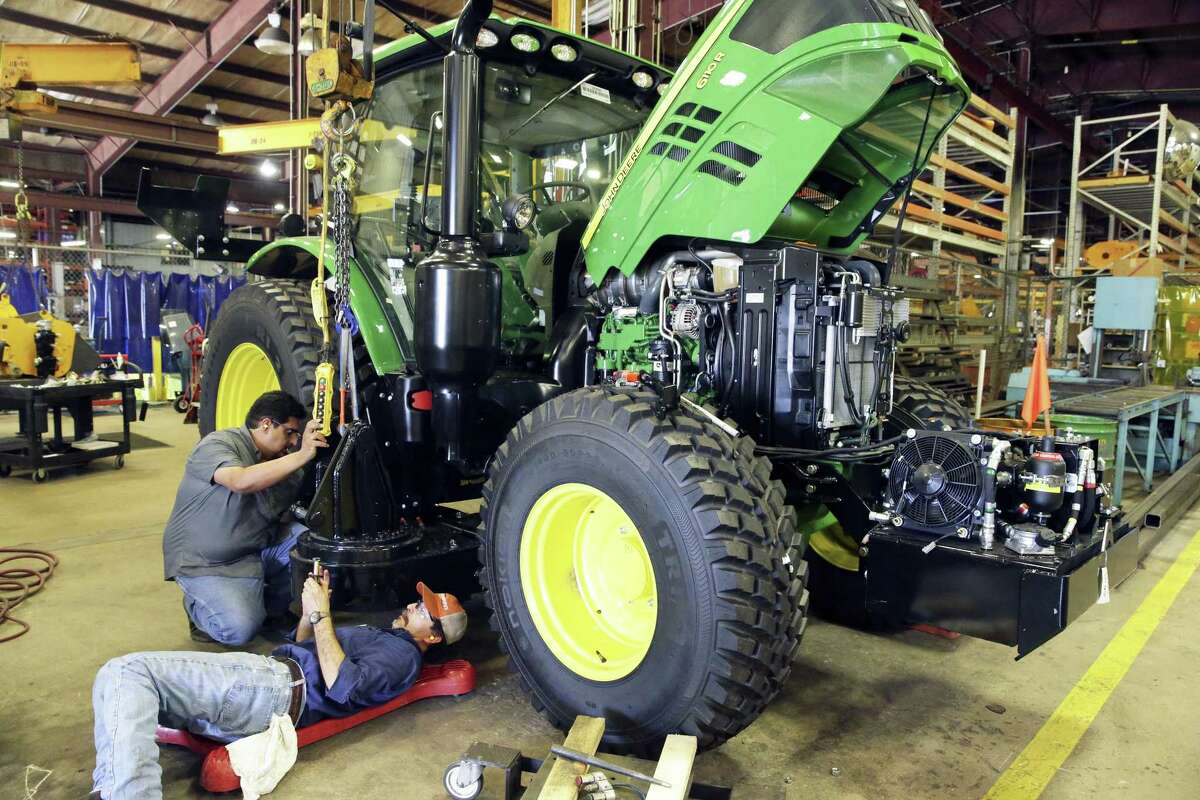 Alamo Group Inc. workers modify a John Deere tractor at the Seguin company’s manufacturing facility. Alamo Group reported record sales and earnings for a first quarter.