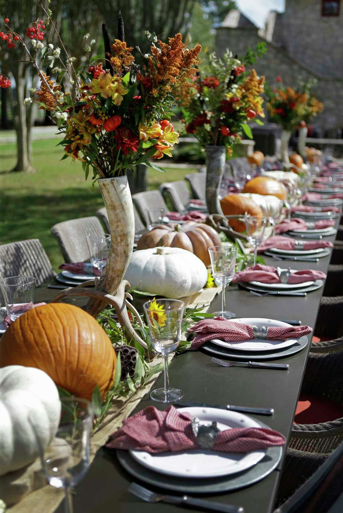 Lucas-Eilers Design Associates designed an outdoor tablescape for 28 using pumpkins, gourds, antlers and tall, skinny vases holding a bouquets of fall colors above the crowd. Tableware courtesy of Kuhl-Linscomb.