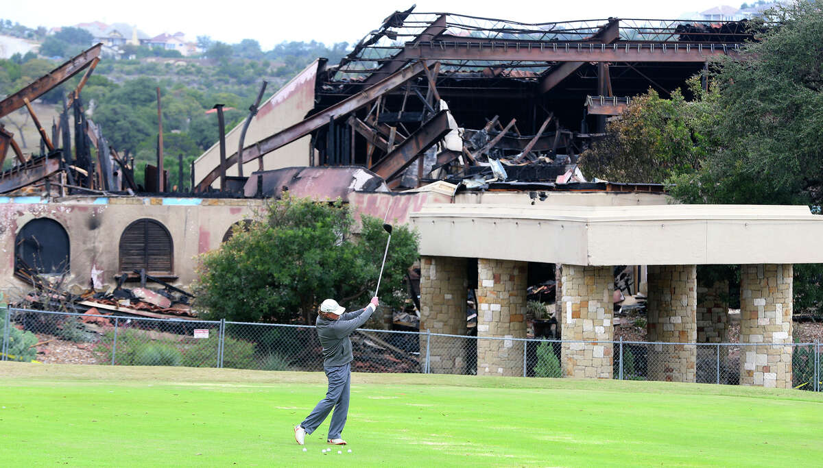 A man golfs in front of the burned club house at the Tapatio Springs Hill Country resort near Boerne, Texas. A fire destroyed the building Saturday night November 4, 2017. Tapatio Springs is on 220 acres in the Hill Country. Its 18-hole golf course recently underwent a $2 million renovation. One of its owners is country music star George Strait.