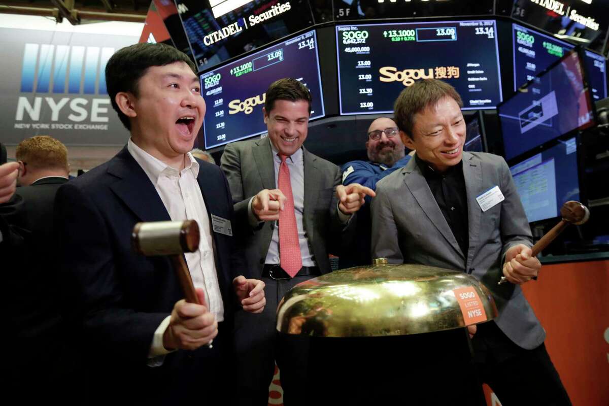 Sogou Inc. CEO Xiaochuan Wang, left, and company Chairman Charles Zhang, right, ring a ceremonial bell as their IPO begins trading, on the floor of the New York Stock Exchange, Thursday, Nov. 9, 2017. New York Stock Exchange President Tom Farley is at center. (AP Photo/Richard Drew)