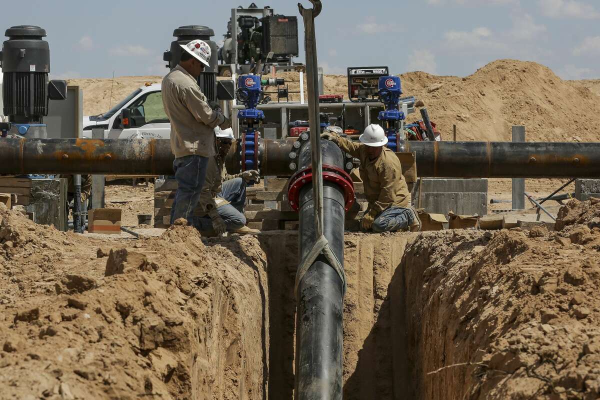 Contractors work to attach the end of a 20-mile water pipeline at Layne Christensen's new property Tuesday, July 18, 2017 in Pecos. The Woodlands based company is building a facility to supply water for hydraulic fracturing operations in the Delaware Basin. ( Michael Ciaglo / Houston Chronicle )