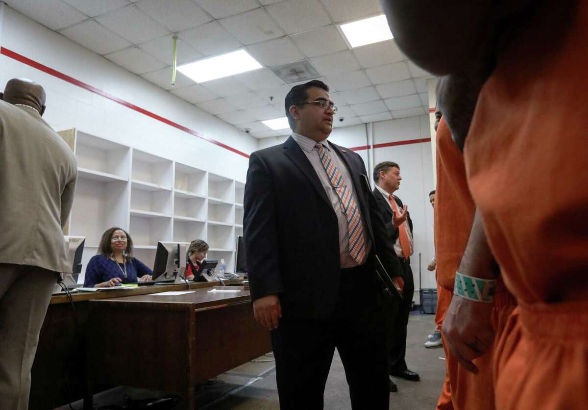 Carlos Rodriguez, center, a defense attorney, speaks with a client Oct. 27, 2017 in the 339th District Court, temporarily located in the Harris County Jail because of damage from Hurricane Harvey.