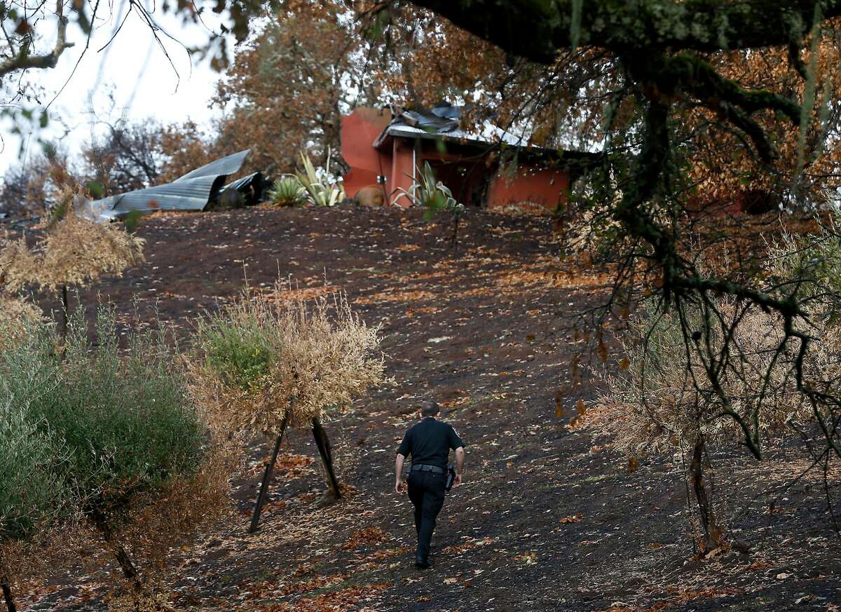 Security guard Joshua Antrim walks towards a damaged home on Bennett Lane in Calistoga, Calif. on Friday, Nov. 10, 2017 next door to the property where authorities believe the Tubbs Fire started. PG&E filed legal papers suggesting that third party electrical equipment, not theirs, may have been the cause of last month's deadly Tubbs Fire.
