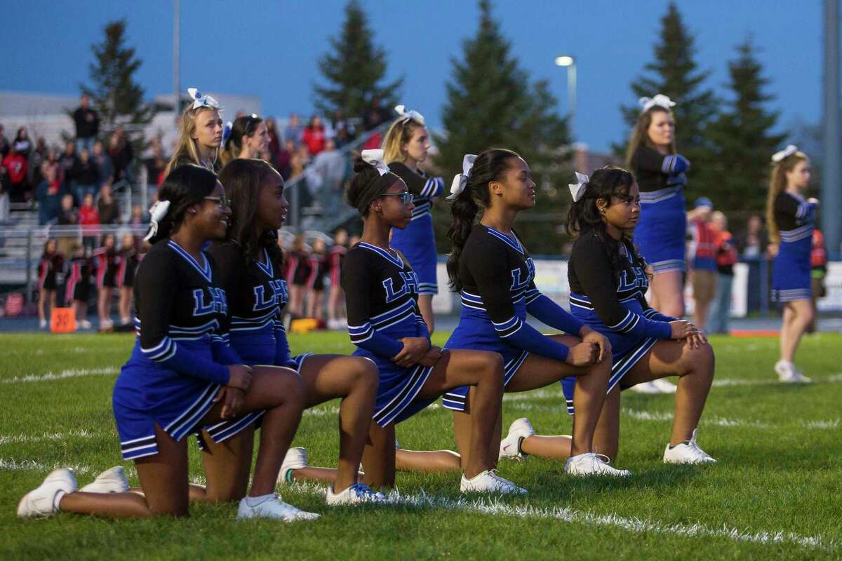 High school cheerleaders in Michigan kneel during the national anthem before a football game Oct. 20, 2017. (Matt Weigand/The Ann Arbor News via AP)