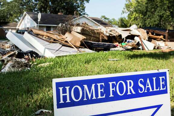 A for sale sign is seen next to a debris pile in the Arbor Oaks neighborhood on Sept. 20, in Houston.