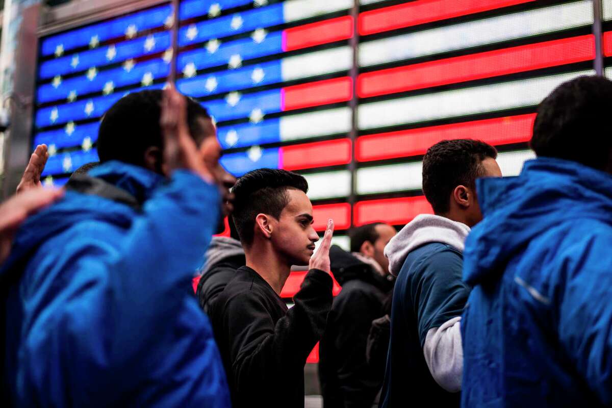 New recruits raise their hands as they take an oath outside the renovated Times Square Military Recruiting Station in New York on November 10, 2017. / AFP PHOTO / Jewel SAMADJEWEL SAMAD/AFP/Getty Images