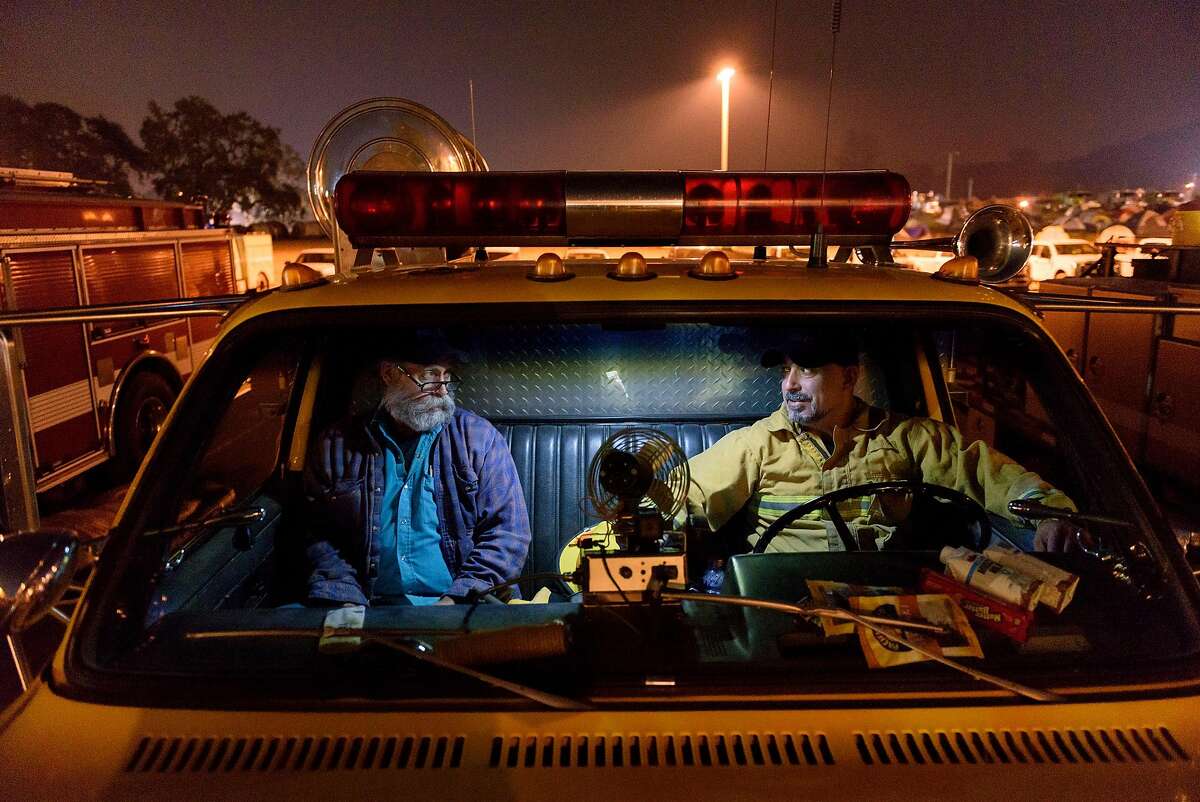 Morgan Territory Volunteer firefighters Richard Nelson, left, and John Khashabi sit and relax in John's privately owned fire truck after a long day of working the fire lines, at the CalFire camp and operations center at the Sonoma County Fairgrounds in Santa Rosa, Calif, on Thursday October 12, 2017.