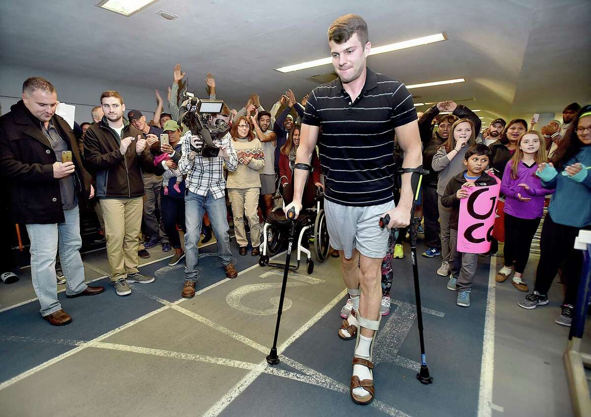 All-American distance runner Collin Walsh, 32, of North Haven crosses the finish-line, surrounded by family, friends, alumni athletes and former teammates during the 55-meter dash at the Southern Connecticut State University alumni track meet, Saturday, Nov. 11, 2017, at Moore Field House in New Haven. Walsh is battling multiple sclerosis, a disease that attacked his body leaving him 80 percent paralyzed a year and a half ago.