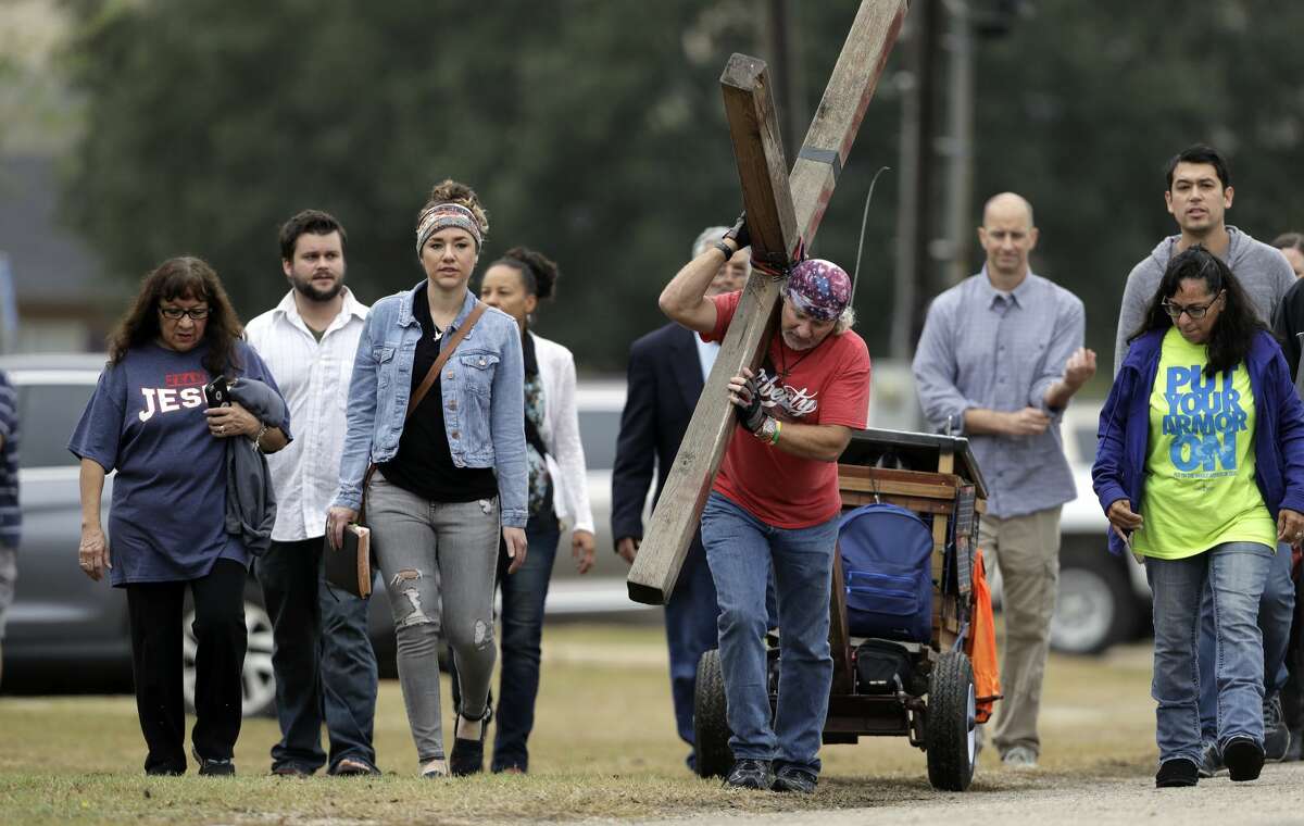 Stephen Hope carries a cross as he and other leave after a worship service for the victims of the shooting at Sutherland Springs Baptist Church, Sunday, Nov. 12, 2017, in Sutherland Springs, Texas, a week after a man opened fire inside the church. Church members will gather this week in a large tent set up at a baseball park. (AP Photo/Eric Gay)