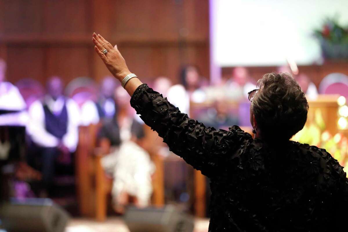 Along with her hand, a worshipper raises voice in song during a Sunday services at Houston's Wheeler Baptist Church, where many members said they were not worried for their safety.