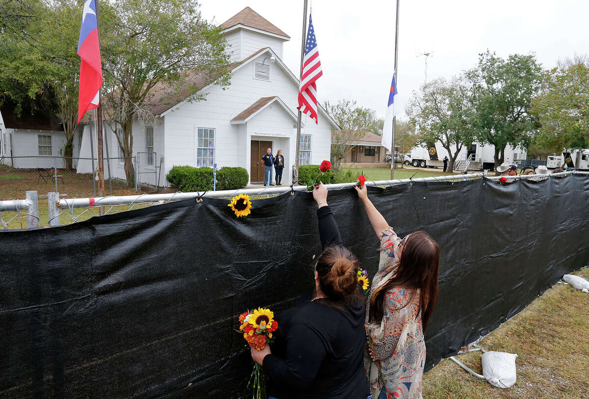 Sisters Rachel Vasquez, left, of San Antonio and Bobby Jo Townsend of Three Rivers leave flowers on the fence outside Sutherland Springs First Baptist Church on Sunday.
