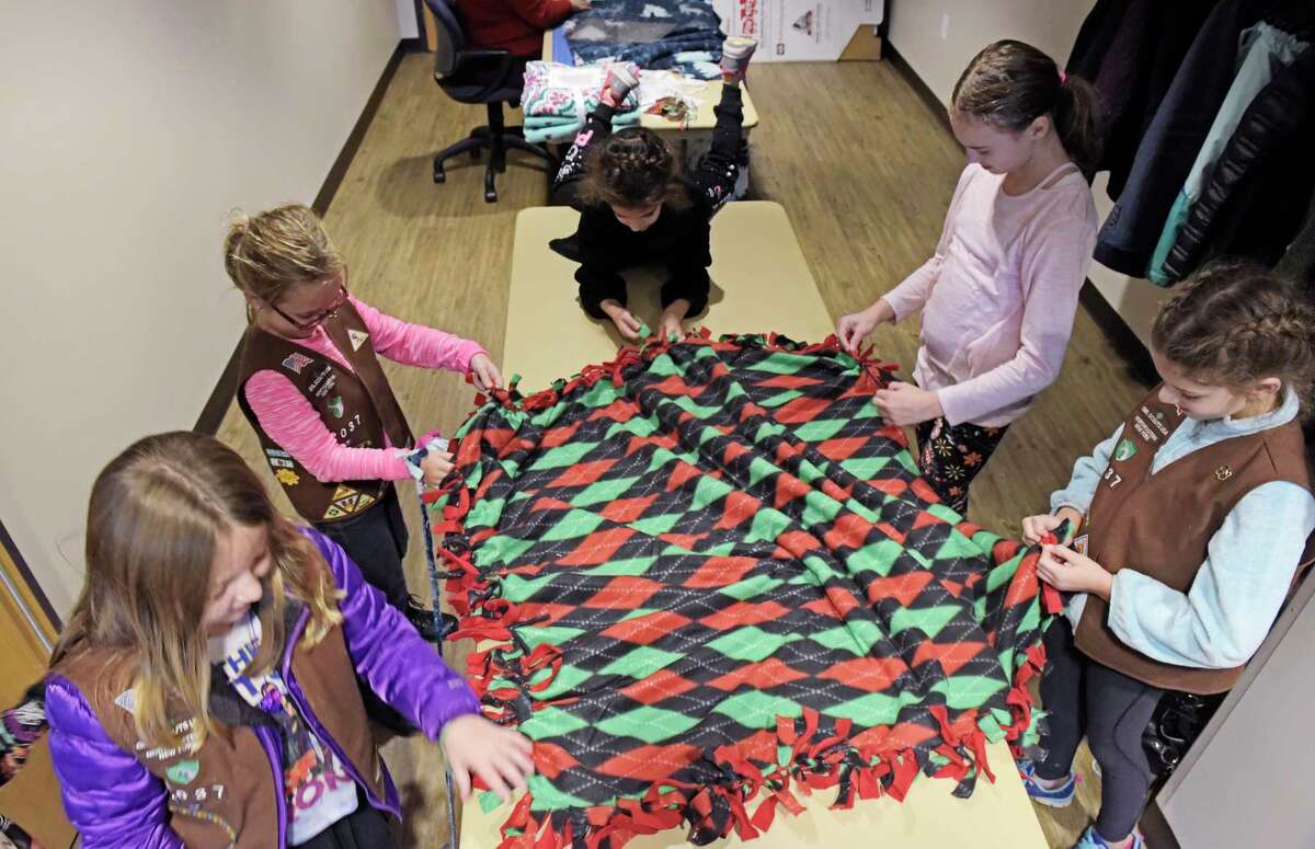Clifton Park Girl Scouts, from left to right, Emma Machiski, her twin sister, Maddie Machiski, Sophia Tsakaloyannis, Grace Anderson and Katerina Tsakaloyannis tie together fringes they cut into material at a blanket cutting and tying party at the Clifton Park Halfmoon EMS on Sunday, Nov. 12, 2017, in Clifton Park, N.Y. Community members gathered on Sunday to create no-sew blankets that will be given out to children through the Toys for Tots Christmas Train. Roughly 500 blankets need to be made by the end of November for Toys for Tots. The Clifton Park Halfmoon EMS is planning anther blanket making party on Saturday, November 18th from 9:00am to 4:00pm. Those interested in helping can contact organizer through email at dkunzelman@cphmEMS.org. The blankets in the past were made by Uncle ShawnOs Hugs, an organization started by Gold Star Mother, Dawn Martin, to honor her son US Marine Sergeant Shawn Martin. Martin was killed in Iraq in 2007. Going forward the organization was unable to make the number of blankets needed by Toys for Tots and so the Clifton Park Halfmoon EMS has stepped in to make the blankets. (Paul Buckowski / Times Union)